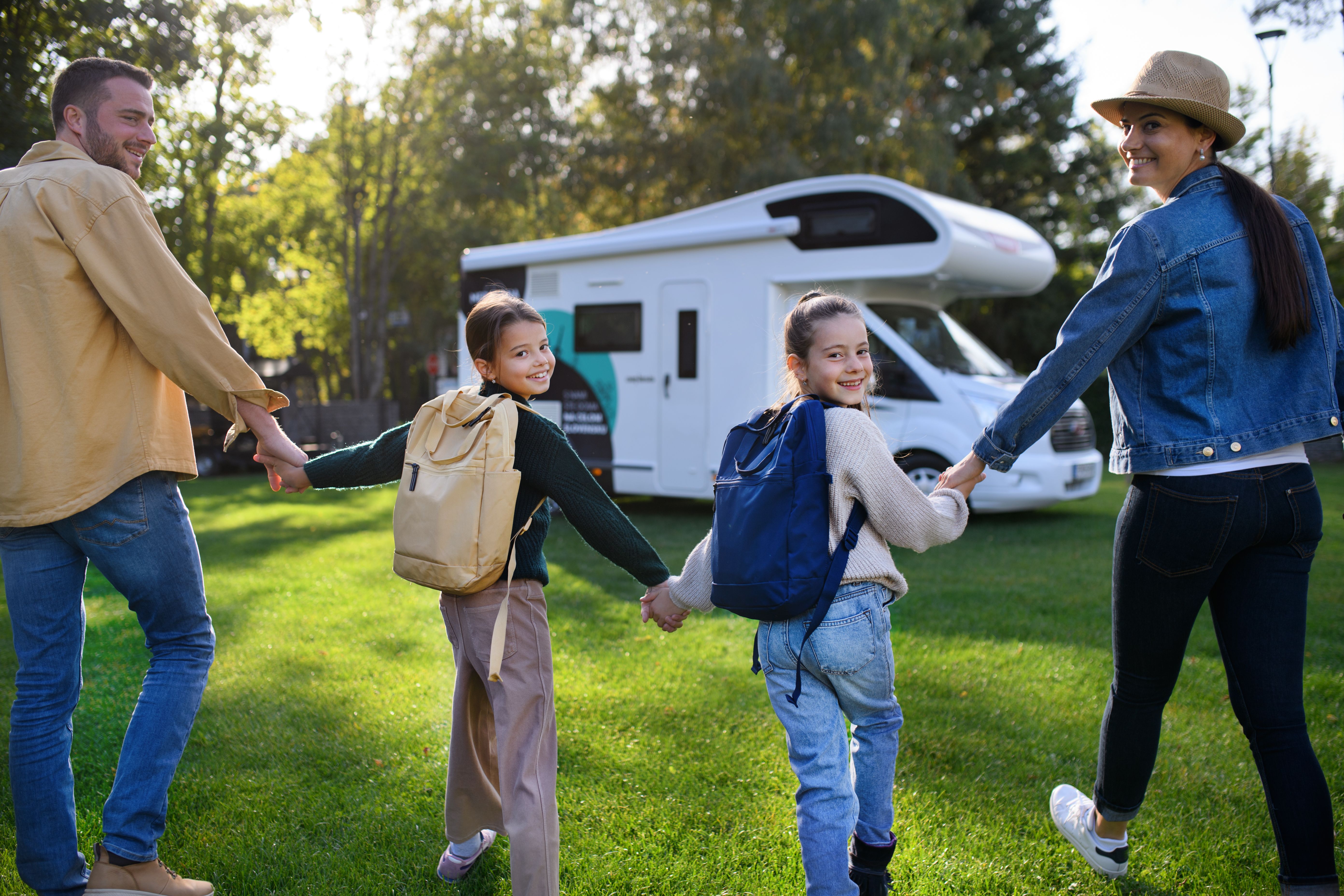 rear-view-of-young-family-with-backpacks-going-to-rv